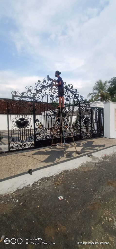 Pintu Gerbang Klasik Jepara Mewah Hitam Emas Judul: Gerbang Klasik Jepara: Penanda Status Sosial Tertinggi Keterangan: Desain Pintu Gerbang Klasik Jepara dengan ornamen Besi Tempa Italia yang presisi. Deskripsi: Gerbang mewah ini menampilkan simetri sempurna dan detail ukiran besi tempa yang menawan, menjadikannya focal point arsitektural yang tak tertandingi untuk hunian klasik.